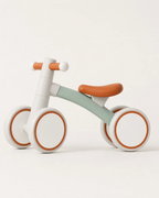 Side view of the Montessori balance bike for 1 year olds, white frame with mint accents and orange padded saddle