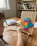 Child solving the Montessori wooden brain puzzle with colorful blocks, challenge cards spread on the table