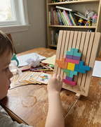 Child solving the Montessori wooden brain puzzle with colorful blocks, challenge cards spread on the table