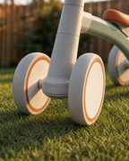 Close-up of the Montessori balance bike's wide wear-resistant wheels on backyard grass