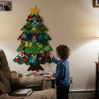 Child pressing a felt ornament onto the wall tree
