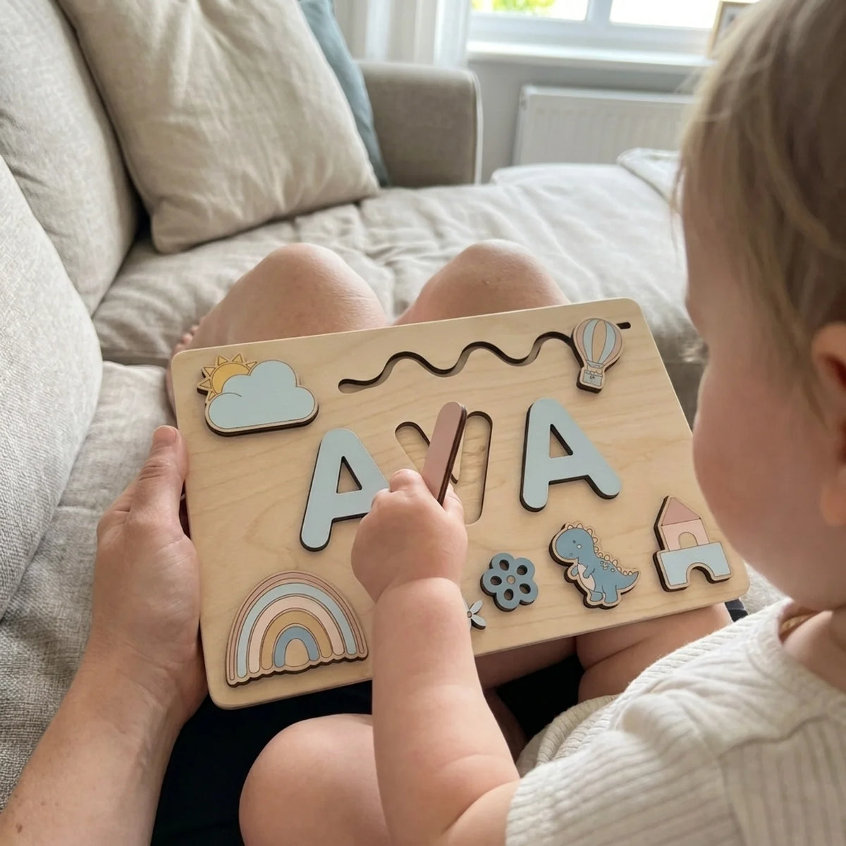 Sky name puzzle on a lap, child lifting a letter piece