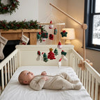 Baby lying in the crib looking up at the Santa & Trees felt mobile