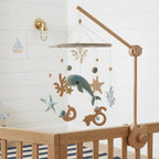 Wooden baby crib mobile, Sage Whale design, clamped on a crib rail in a ocean nursery