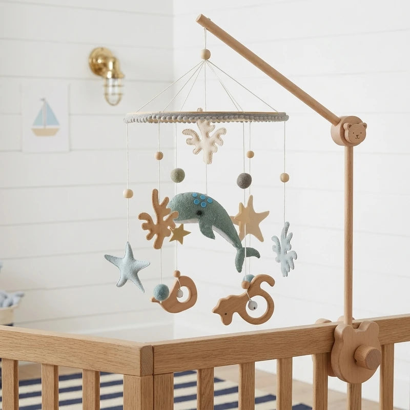 Wooden baby crib mobile, Sage Whale design, clamped on a crib rail in a ocean nursery