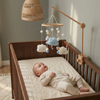 Baby lying in the crib looking up at the Smiling Clouds felt mobile