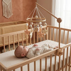 Baby lying in the crib looking up at the Beige Owl felt mobile